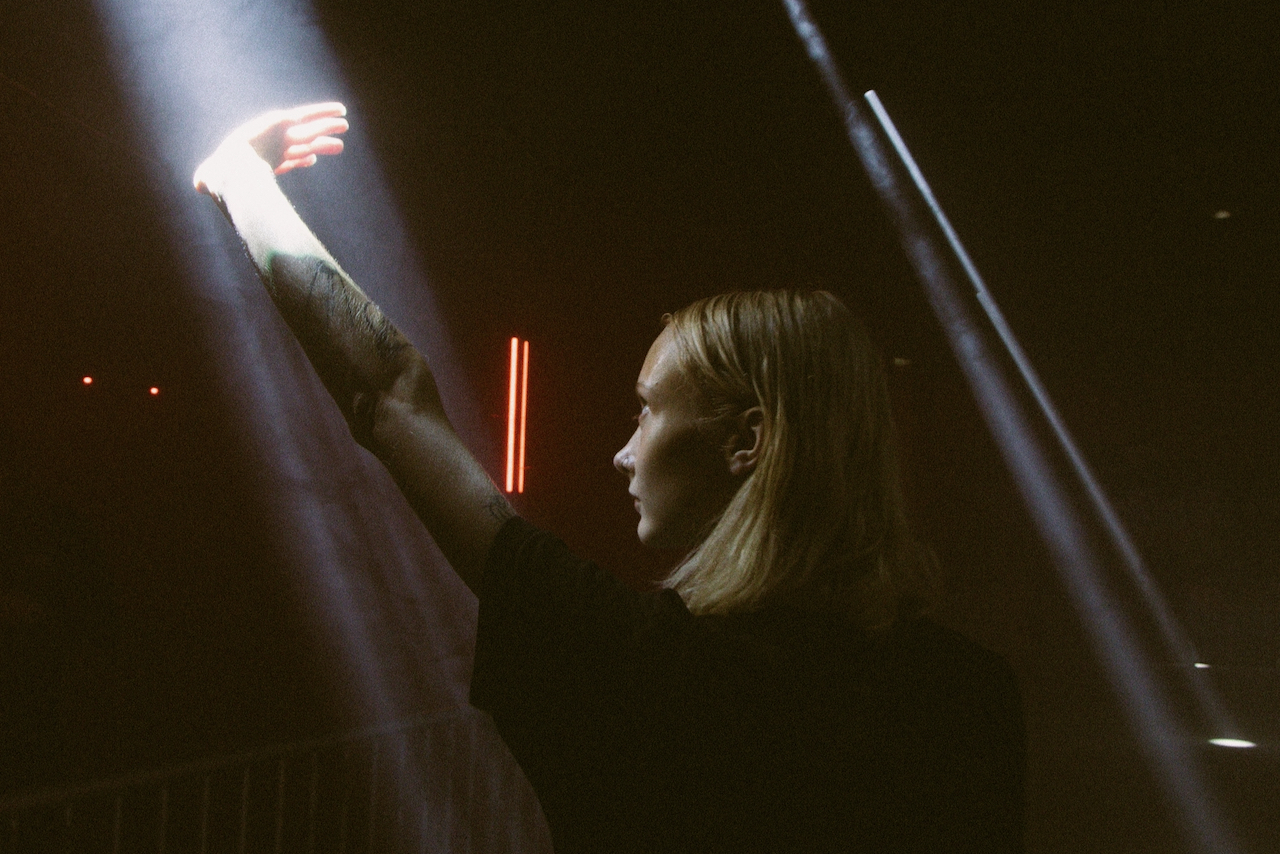 Women puts up hand towards beam of light