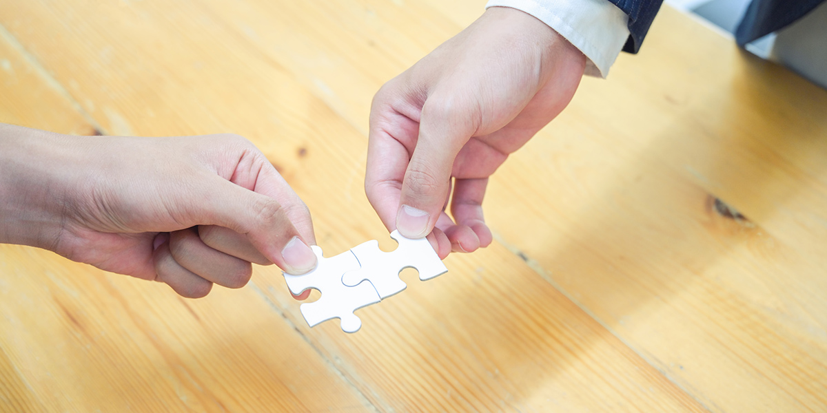 Two hands holding jigsaw puzzle pieces