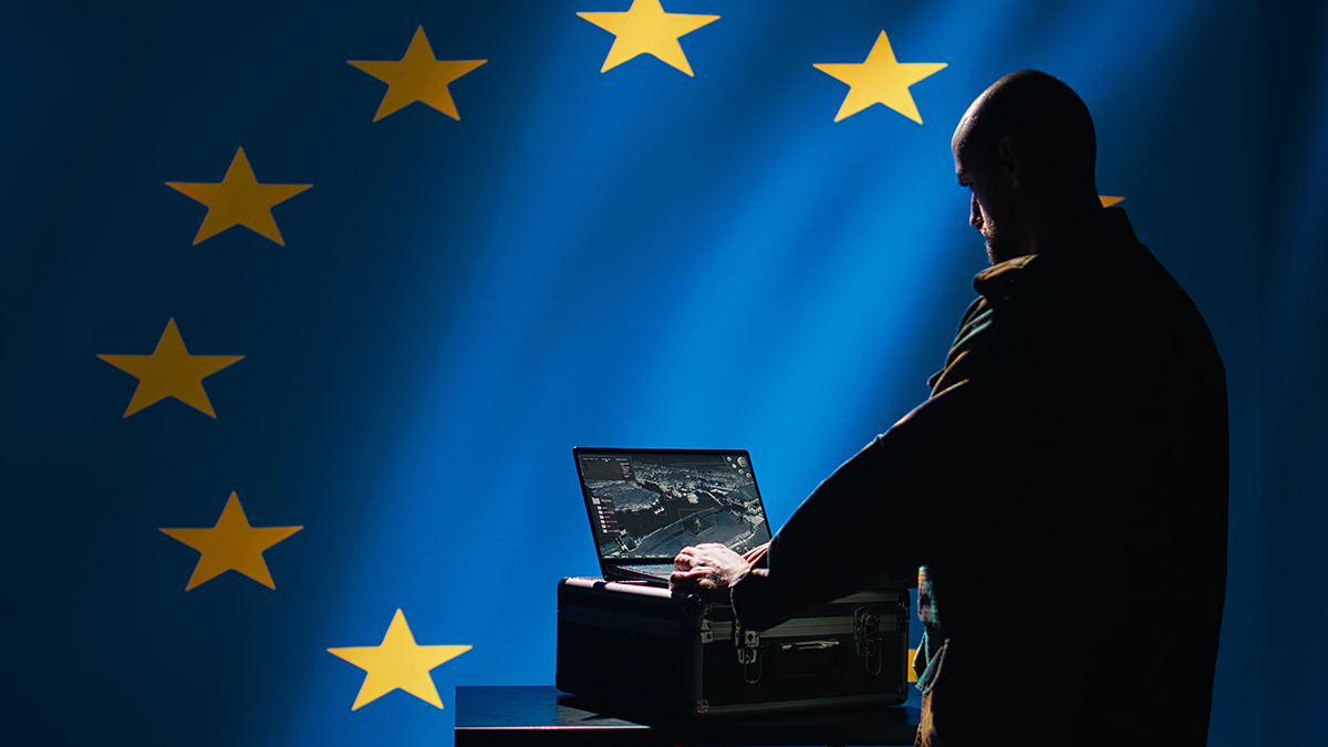 EU flag with shadowy figure using a laptop. Freepik Premium photo used under licence..